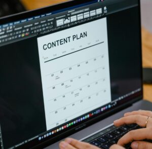 Close-up of hands typing on a laptop displaying a content plan document, ideal for business or marketing content.